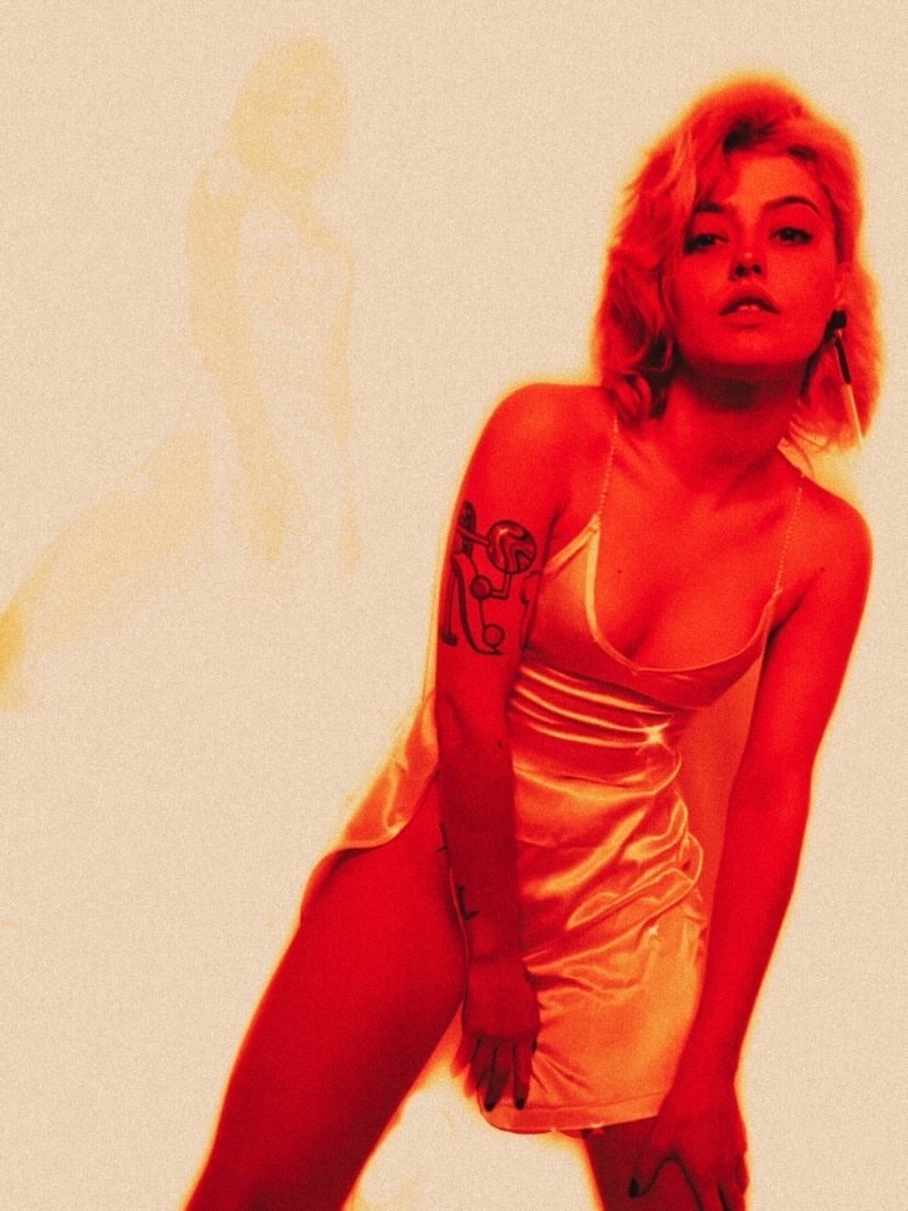 Alba Reche wearing a custom satin mini dress designed by Júlia Puñet under cinematic red lighting.