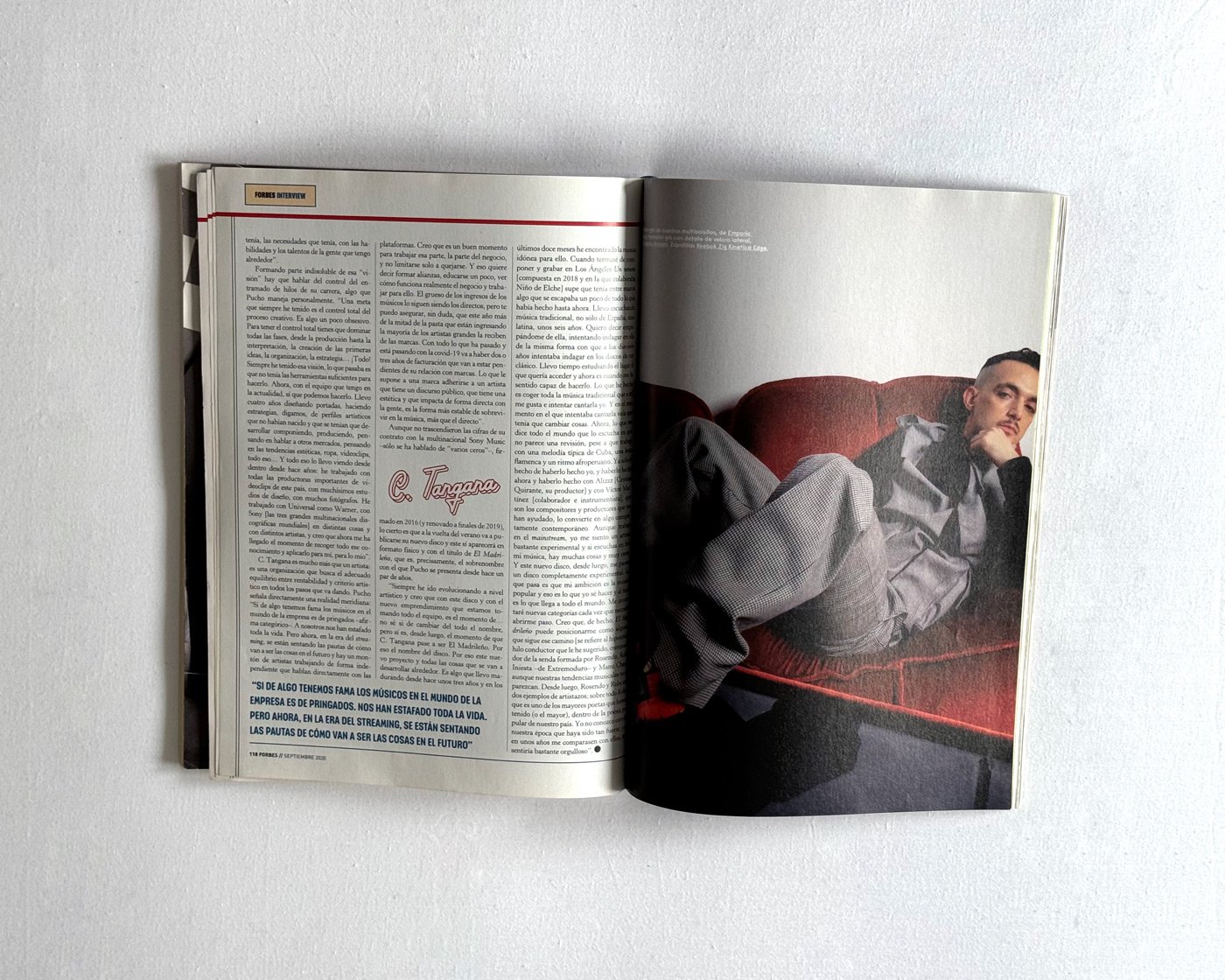 C. Tangana reclining on a red sofa in Forbes España editorial photographed by Javier Ruiz styled by Júlia Puñet