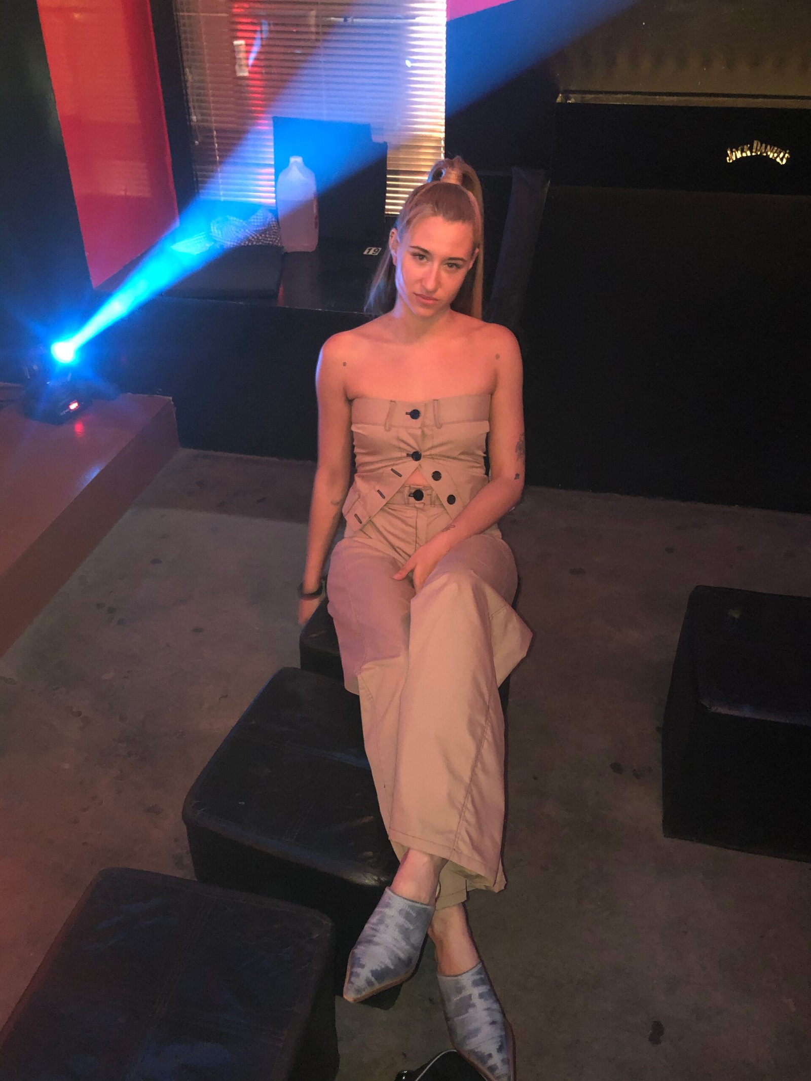 Kyne seated backstage wearing custom beige stage outfit during live performance in Madrid